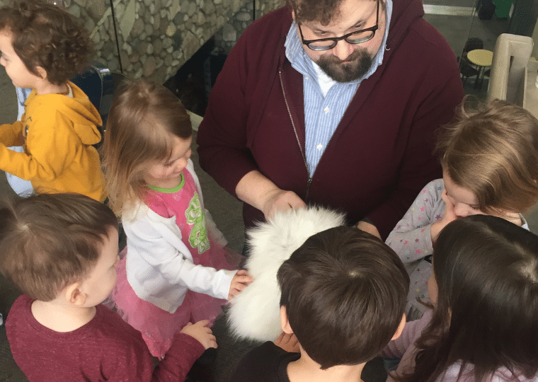 An adult showing a group of 3 year olds a patch of white fur