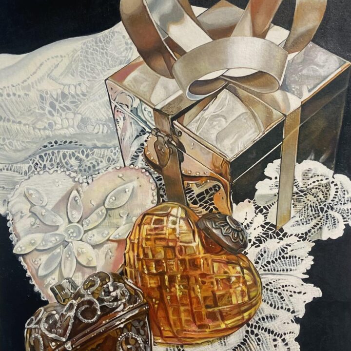 A still life with a reflective gift box and ribbon, amber glass heart, and decorative heart with lace background.