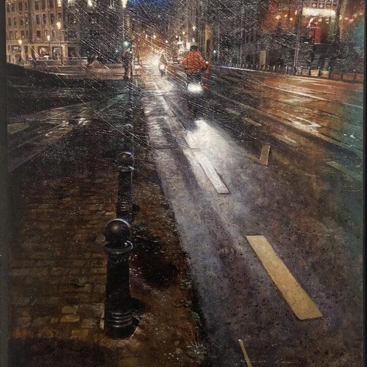 A wet city street at night with cyclists and glowing reflections.