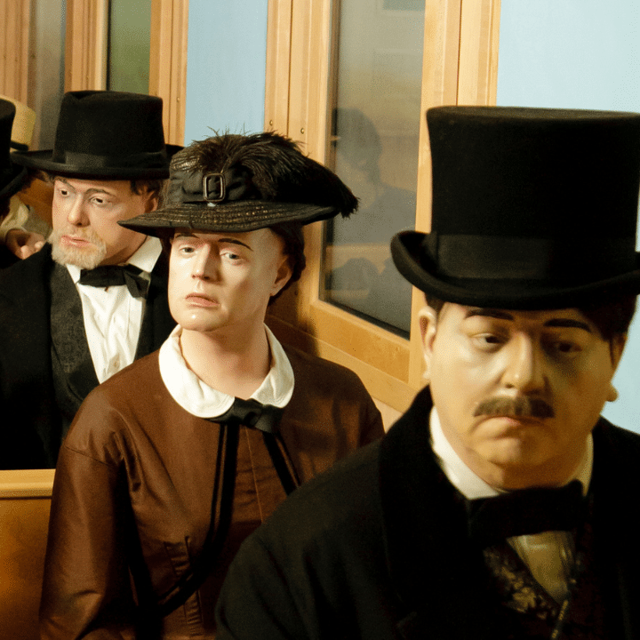 Wax figures in early 20th-century clothing in a train car setting.
